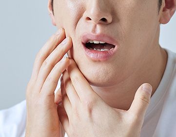 턱 통증을 손으로 짚고 있는 외상 및 긴장 스트레스로 인한 턱관절 장애 예시